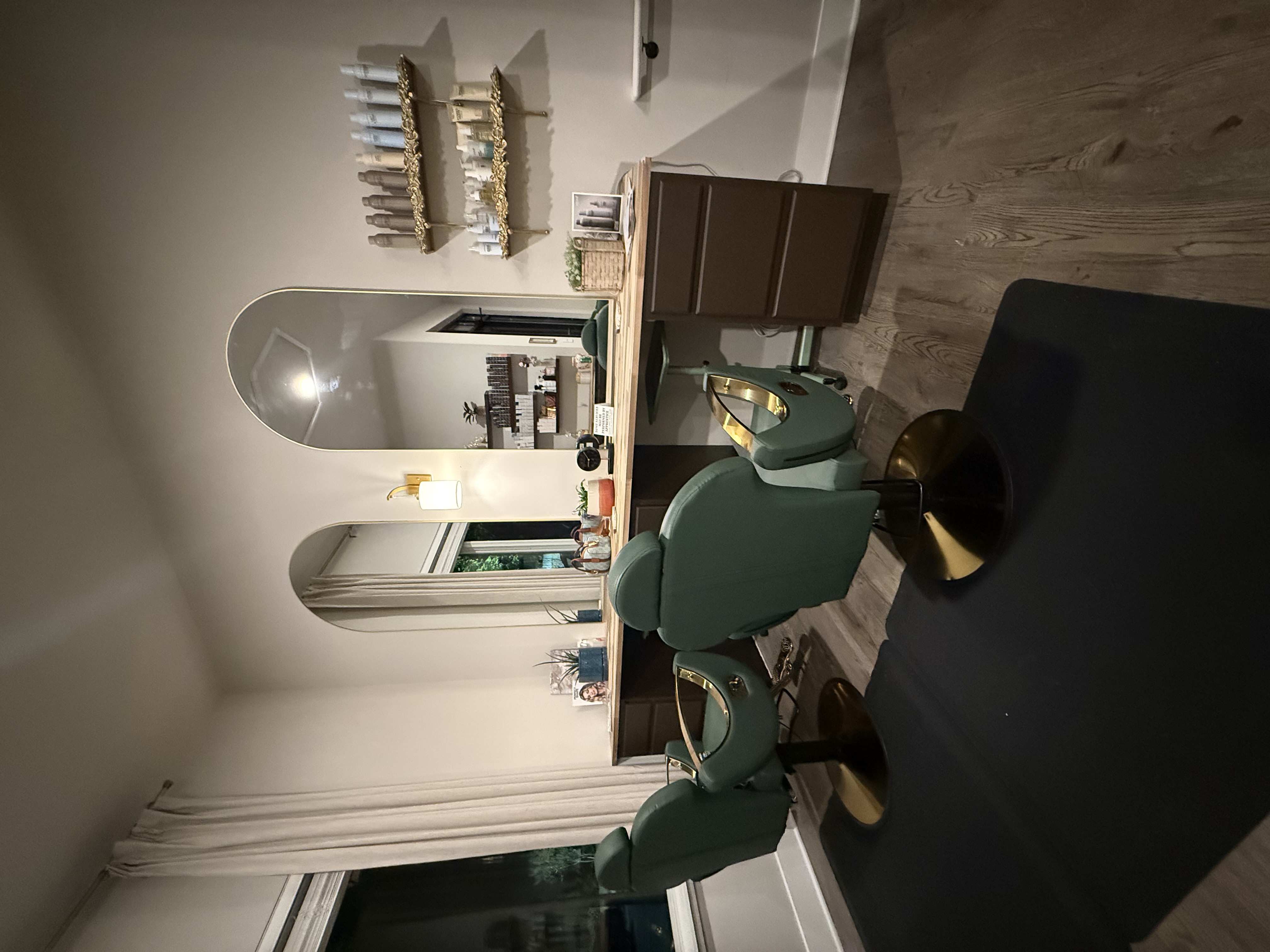 Grand Collective styling station with green salon chairs, mirrors, and retail shelves