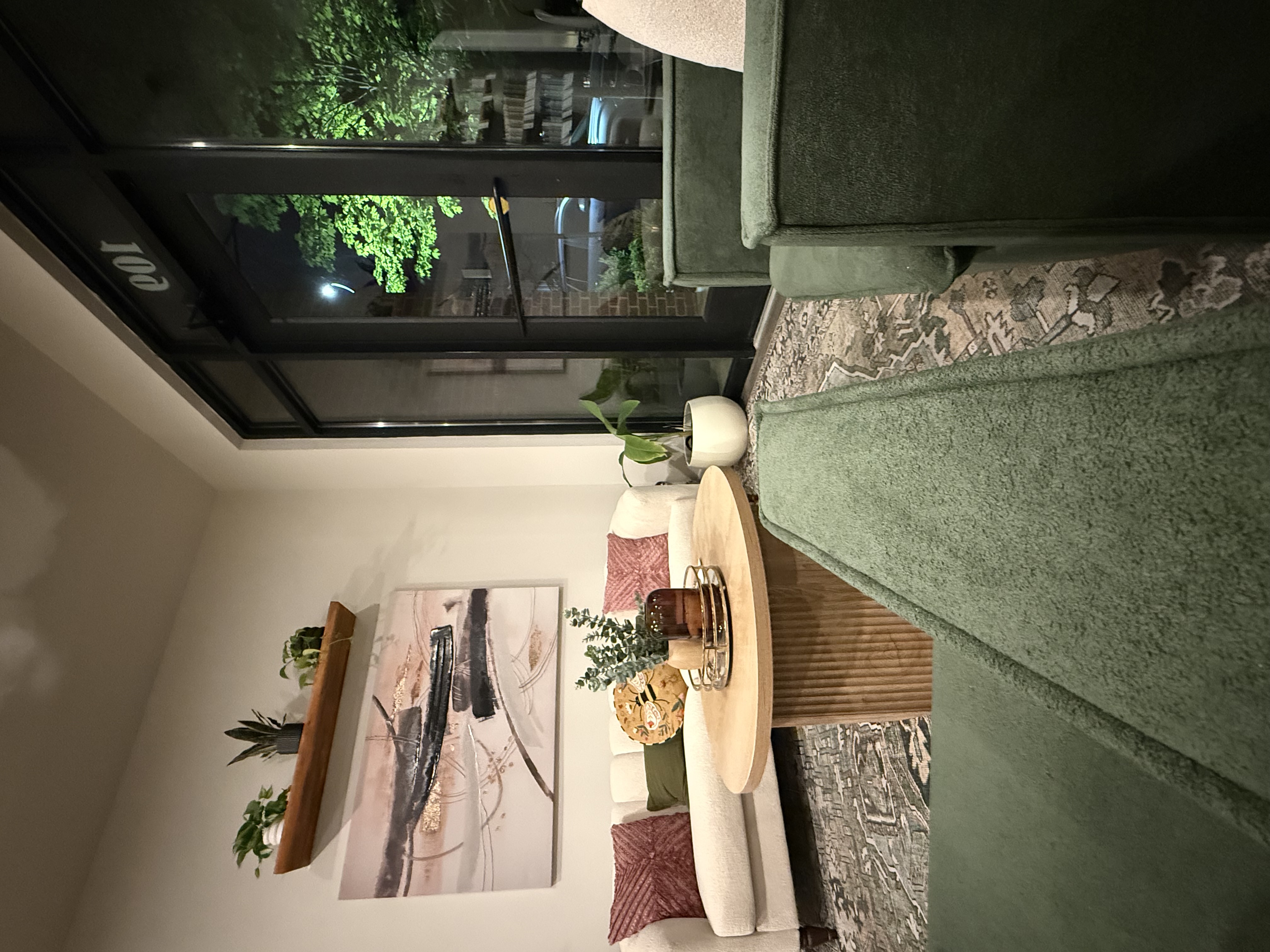 Grand Collective salon lounge with green chairs, cream sofa, plants, and artwork